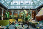 Hotellobby mit Glasdach, exotischen Pflanten und Tischen