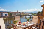 Terrasse mit gedecktem Tisch und Stühlen mit Blick auf Arno in Florenz