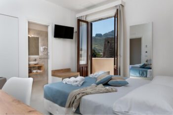 Hotelzimmer mit Doppelbett in Blautönen und Blick auf Berg