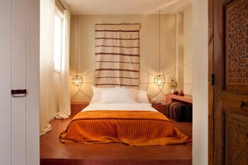 Einblick in Schlafzimmer mit niedrigem Doppelbett und Hängelampen