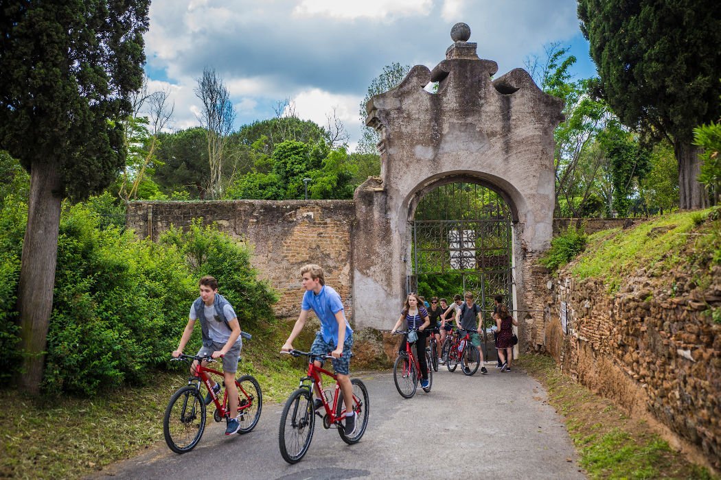 Young people on bicycles by a stone gate