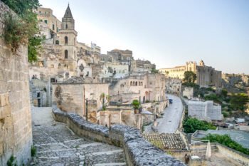 Blick auf Gasse von Matera mit tuffsteinfarbenen Häusern und Kirchturm