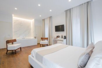 Helles Hotelzimmer mit weißem Bett und Badewanne