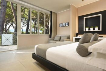Modernes Hotelzimmer mit Bett und Terrassentür zu Pinienwald