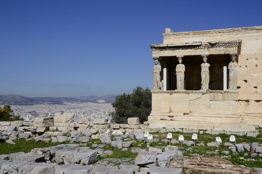 Tempel mit Säulen in Form von Frauenstatuen mit Stadt im Hintergrund