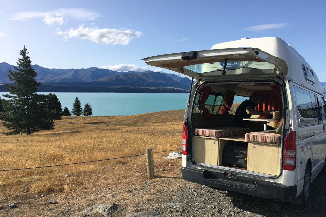 Offener Camper mit See und Bergen im Hintergrund