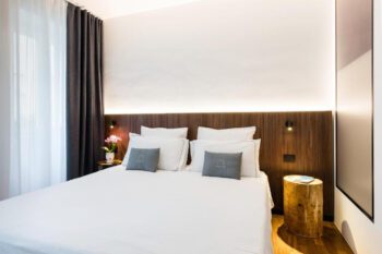 Hotelzimmer mit Weißem Doppelbett und dunkler Holzwand