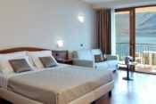 Hotelzimmer mit Bett und Balkon mit Seeblick