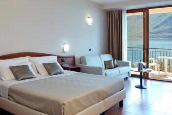 Hotelzimmer mit Bett und Balkon mit Seeblick