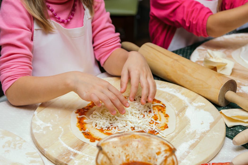 Kinder die Pizzateig belegen bei Kochkurs in Florenz