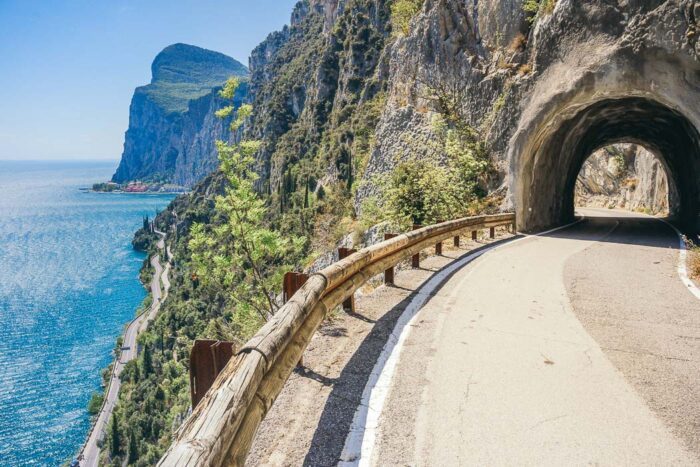 Die Straße Strada della Forra mit Tunnel, Felswand und Gardasee links