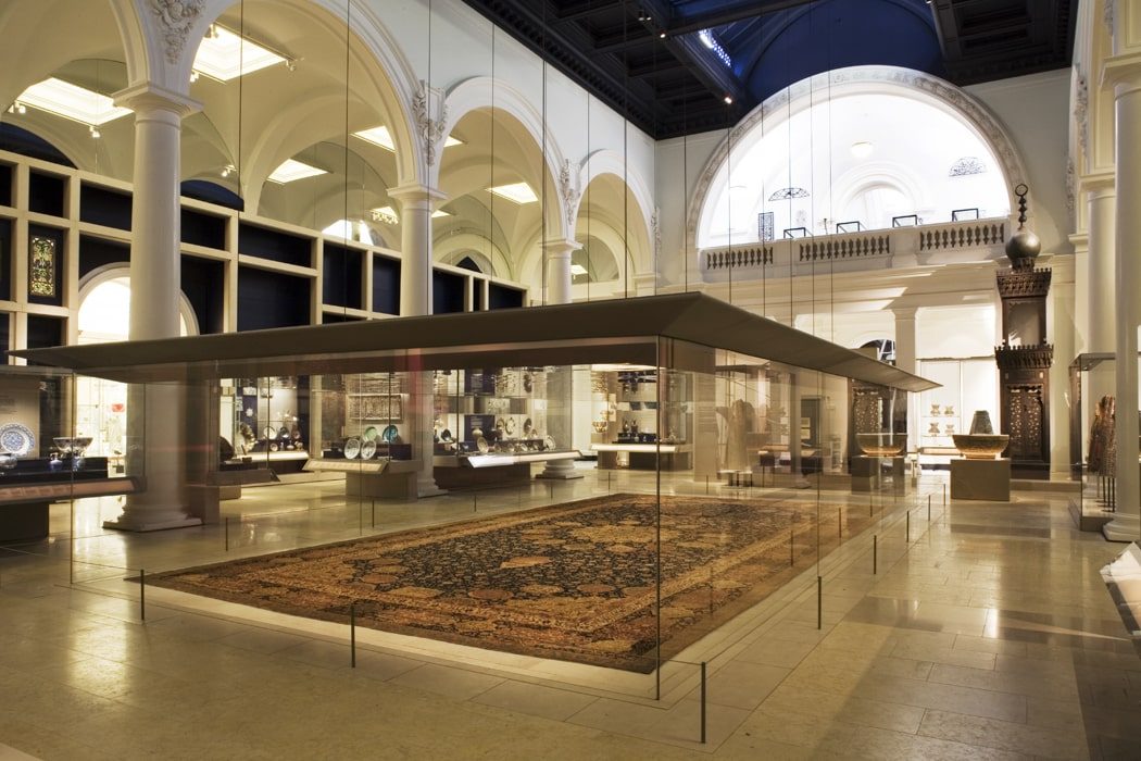 Museumssaal im Victoria & Albert Museum mit großem Teppich umgeben von einer Glaswand