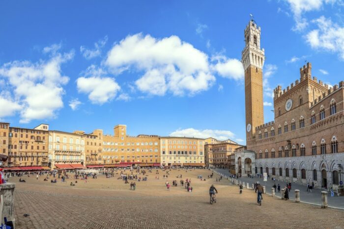 Großer Platz von Gebäuden umgeben und hohem Glockenturm in Siena