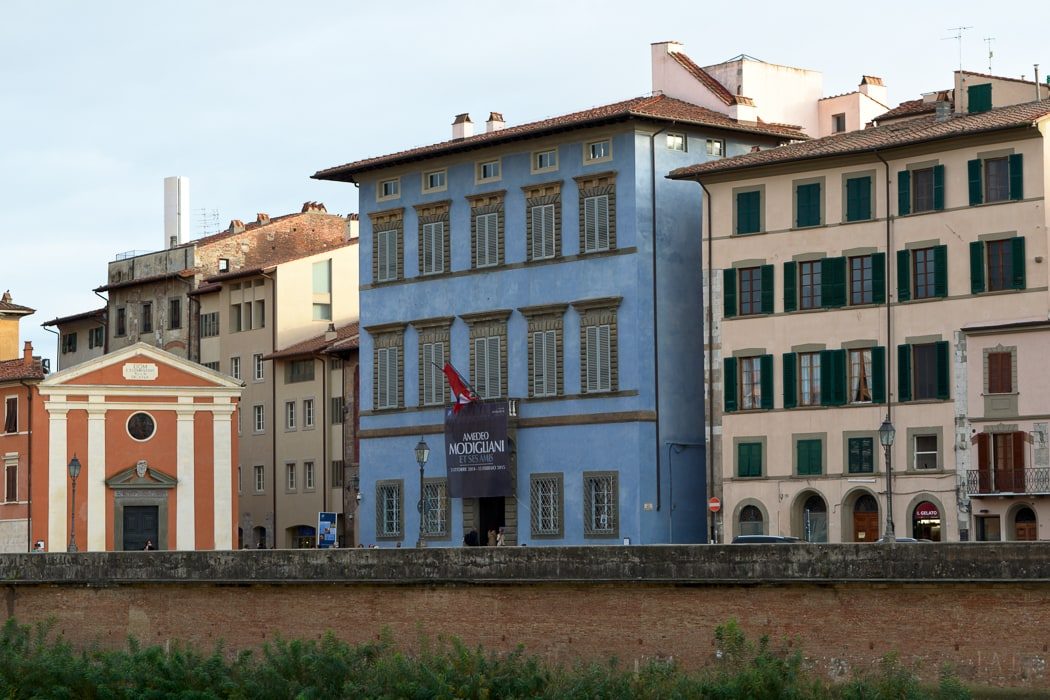 Blau angestrichener Palast an Flussufer mit hellen Palästen drumrum 