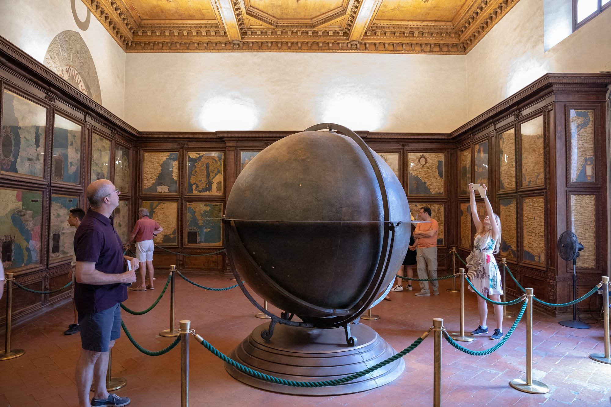 Raum mit großem Globus aus Holz und Landkarten an der Wand