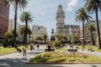 Die Plaza Independencia in Montevideo mit Palmen, Bauten, einem Denkmal und Menschen auf Bänken