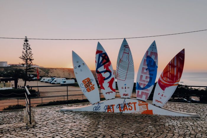 Sagres Surfboard-Monument im Sonnenuntergang, mit Campervans im Hintergrund