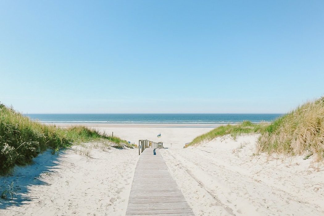 Strandaufgang auf Juist - Holzsteg zwischen den Dünen mit Blick aufs Meer.