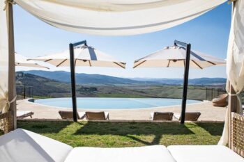 Zwei weiße Sonnenschirme an einem Pool mit weitläufiger Aussicht in den Capanna Suites auf einem Weingut in der Toskana
