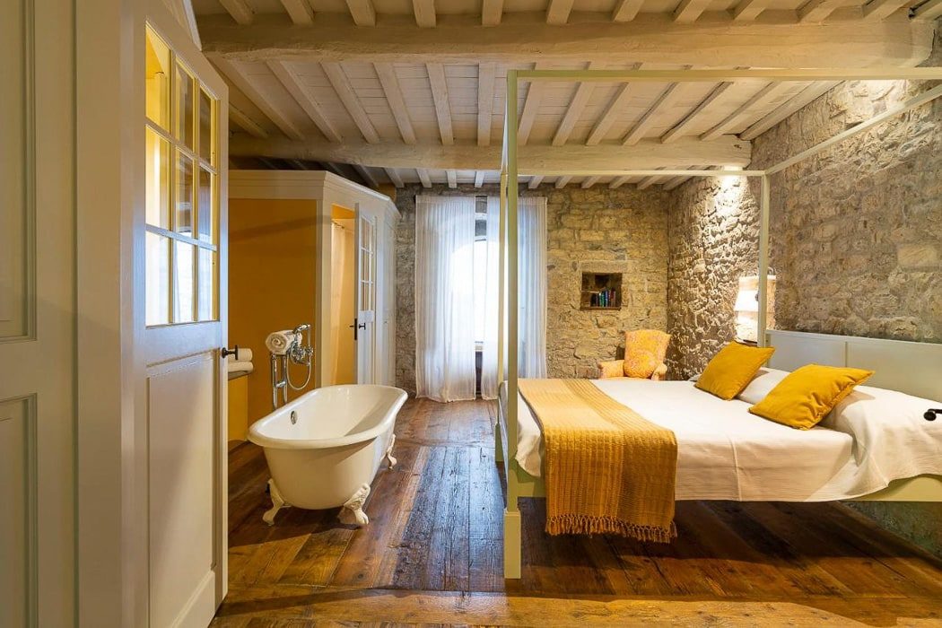 Großes Zimmer mit Doppelbett mit oranger Decke und Holzbalkendecke