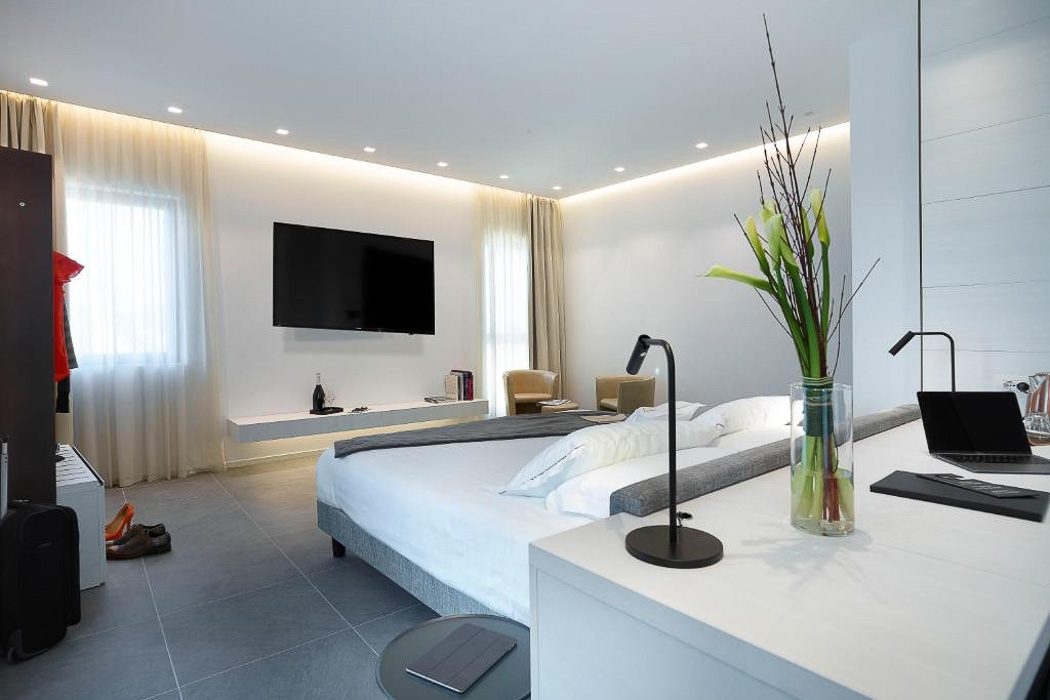 Hotelzimmer in hellen Tönen, modernem Design, Doppelbett und Fernseher