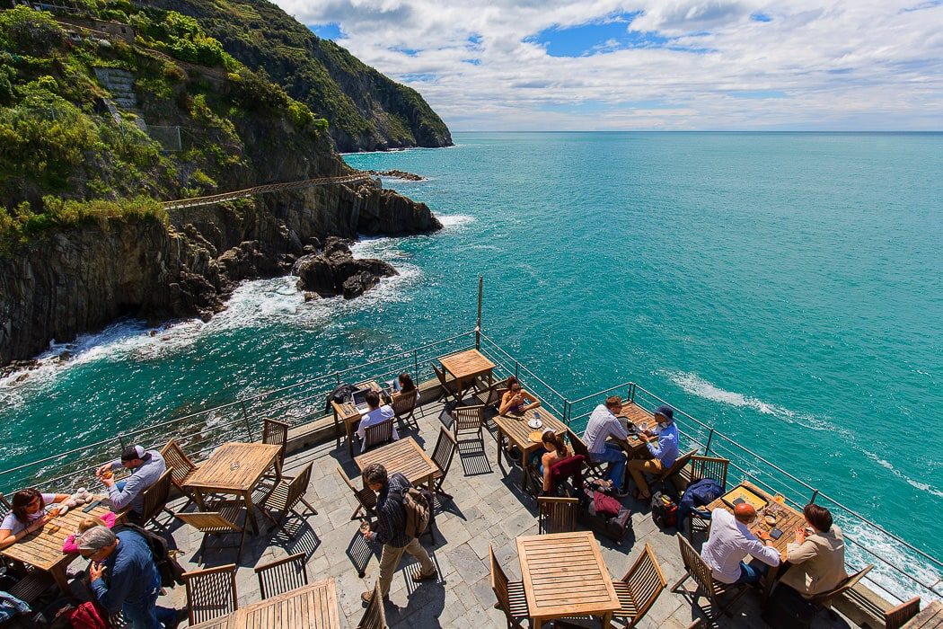 Terrasse mit Tischen direkt über dem Meer