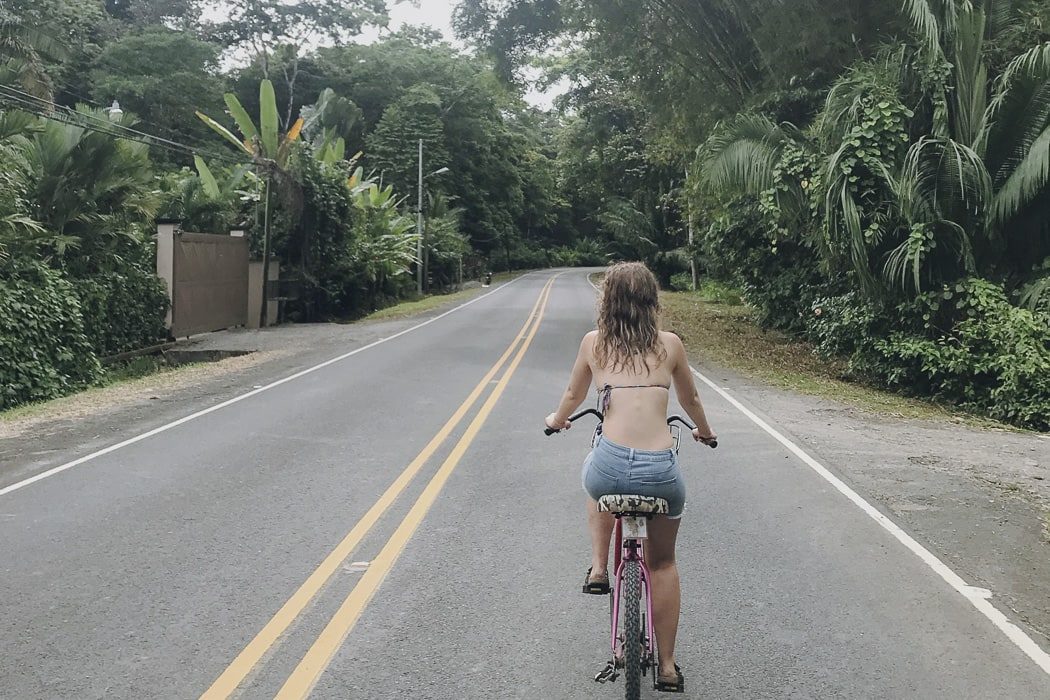 Frau fährt auf einem Fahrrad auf einer Straße in Puerto Viejo