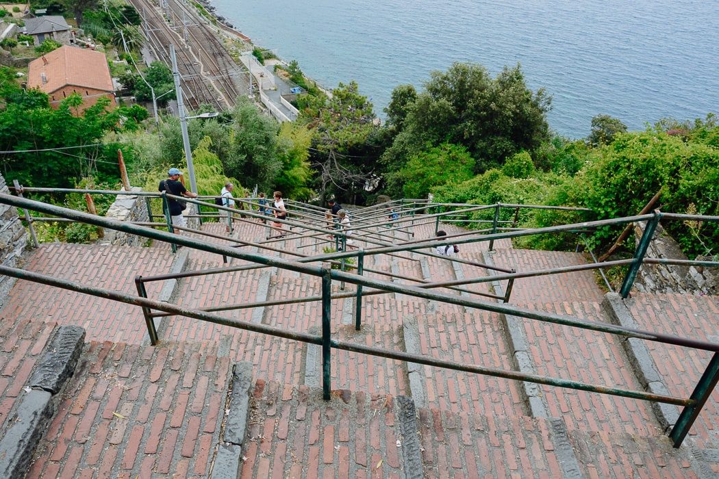 Treppe mit breiten Stufen mit Zuggleisen weit unten und Meer