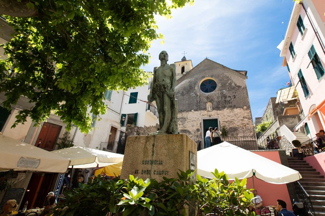 Piazza mit Kirche mit rundem Fenster, Statue und weiße Sonnenschirme von Cafés