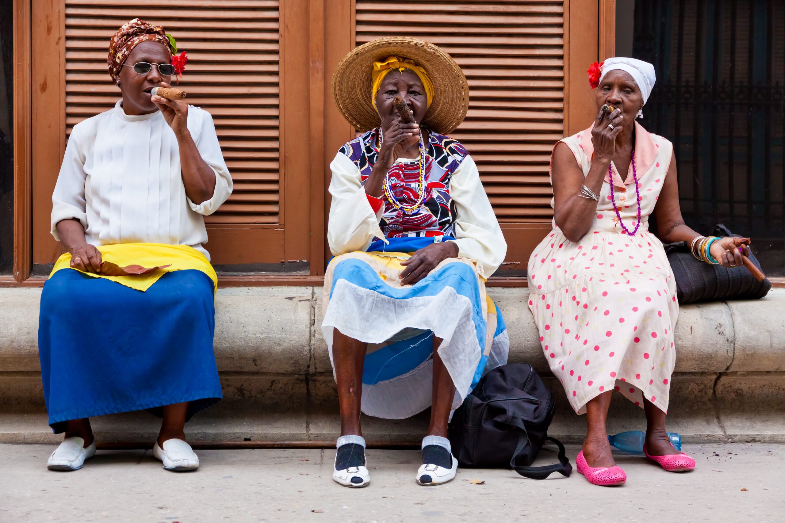 Kubanerinnen, die am Straßenrand Zigarren rauchen