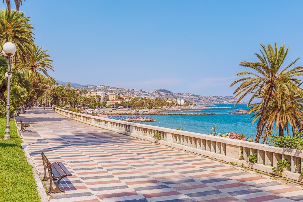 Blick auf Strandpromenade mit schachbrettartigem Boden und Palmen 