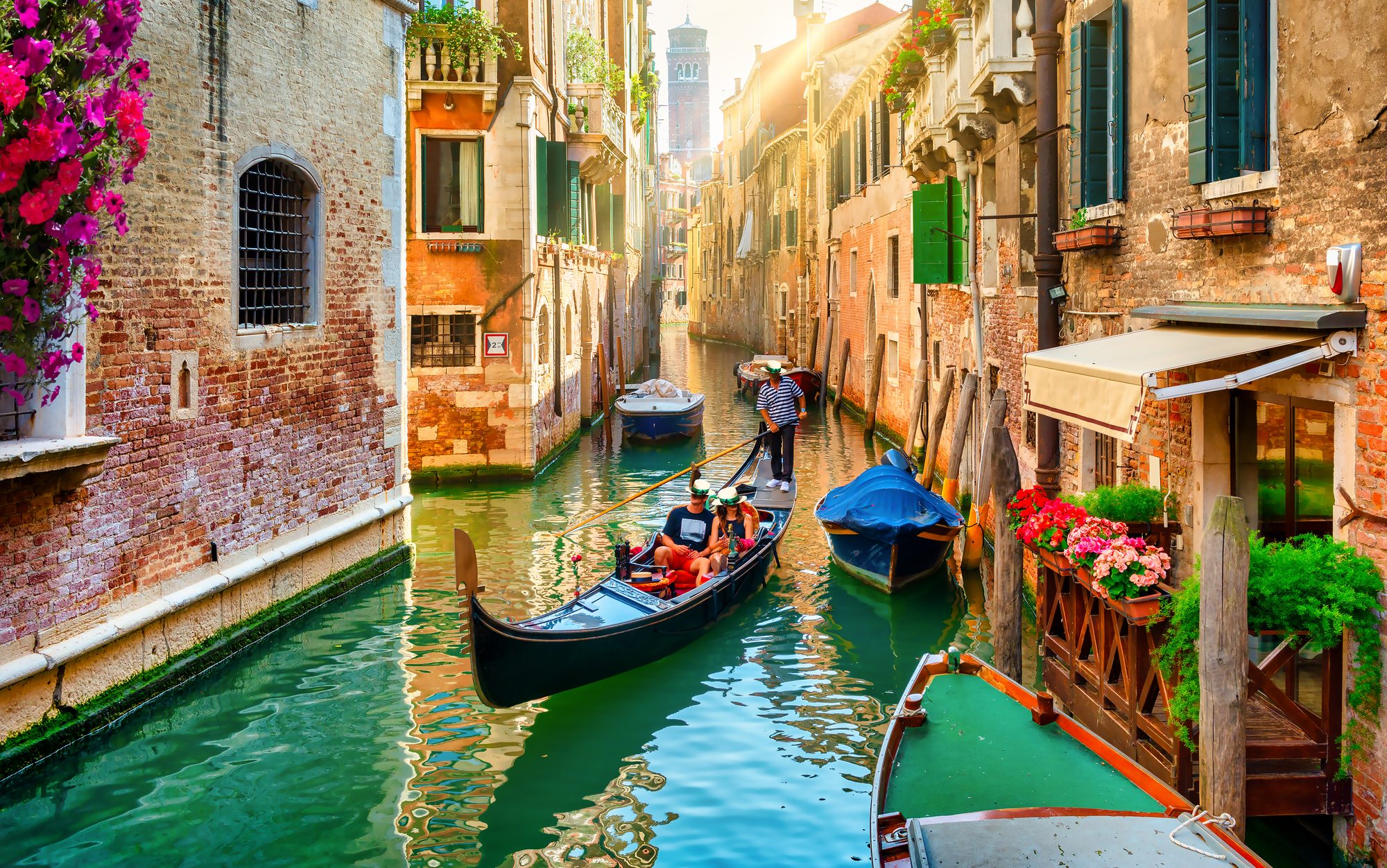 Gondel mit zwei Personen auf hellgrünem Wasser im Kanal von Venedig