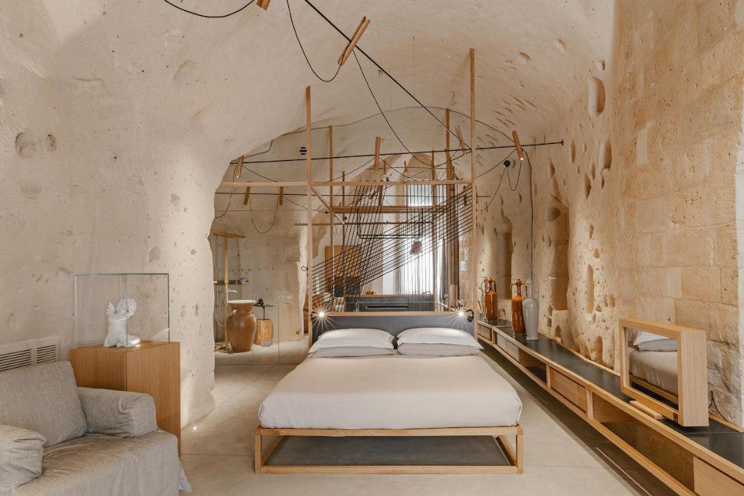 Minimalistisch und hoch modern eingerichtetes Höhlenzimmer mit hellen Steinwänden und Doppelbett
