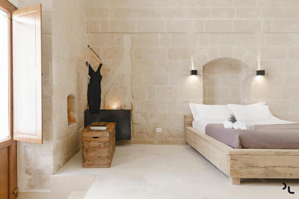 Zimmer mit hellen Steinwänden und modernes Holzbett