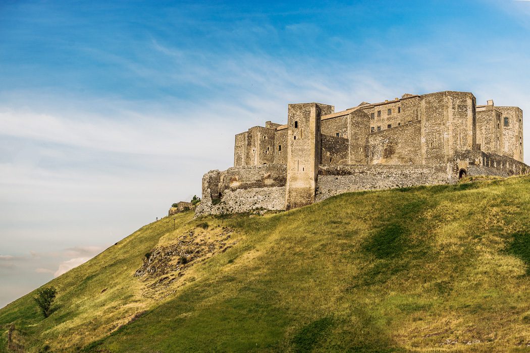 Mittelalterliche Burg auf grünem Hügel mit hohen Burgmauern