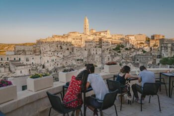 Terrasse mit Blick auf die Sassi von Matera mit zwei Paarern, die an Tischen sitzen