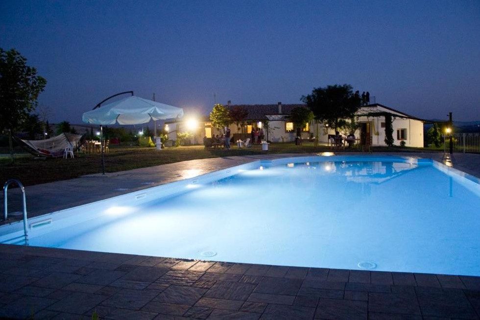 Großer Pool mit Haus im Hintergrund am Abend
