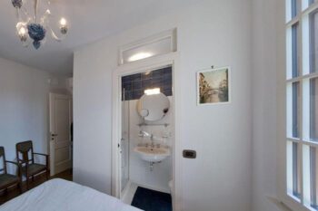 Schlafzimmer mit Blick auf offene Badezimmertür und Waschbecken