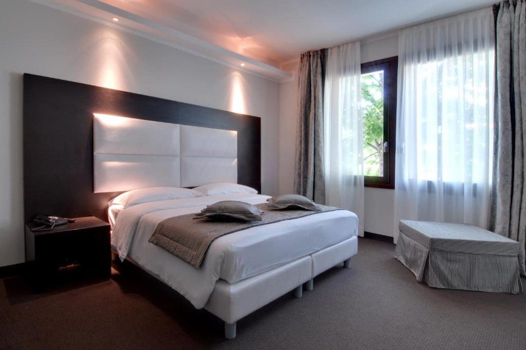 Hotelzimmer mit modernem Doppelbett mit weißem Kopfende
