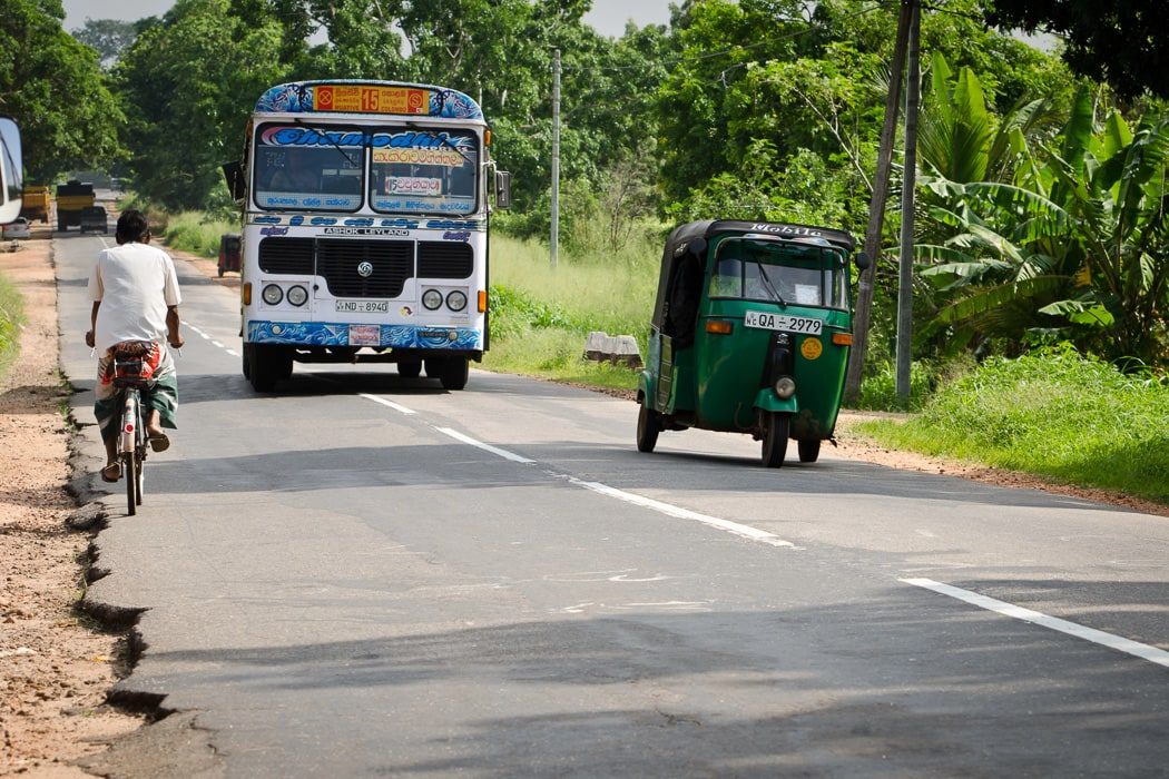Ein Bus, ein Tuk Tuk und ein Fahrradfahrer auf einer Straße in Sri Lanka